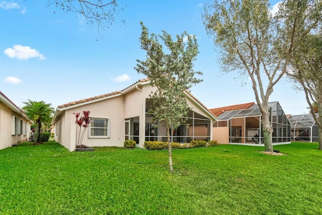 rear view of property with stucco siding, a tiled roof, and a yard