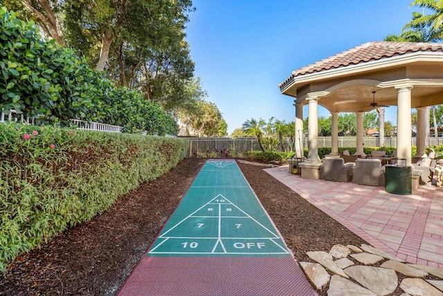 view of community featuring fence and shuffleboard