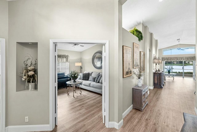 hall featuring baseboards, high vaulted ceiling, and wood finished floors
