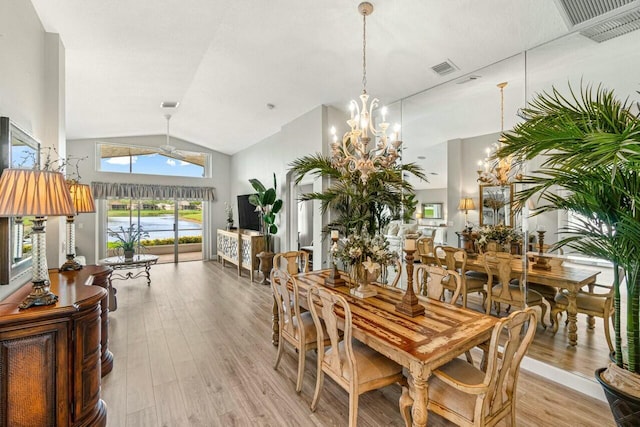 dining room with a notable chandelier, light wood finished floors, visible vents, and vaulted ceiling
