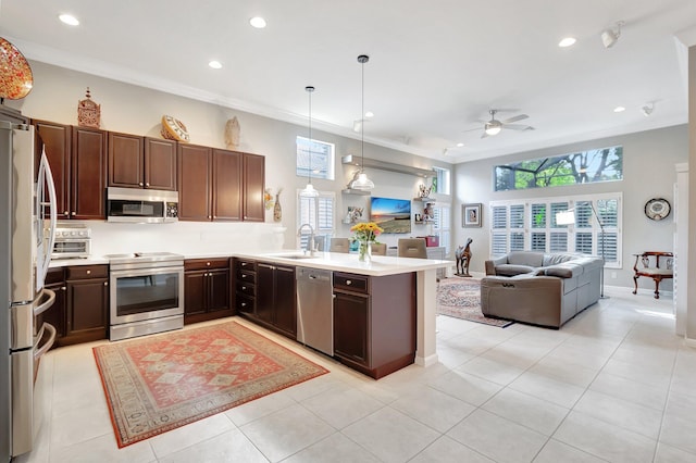 kitchen with a peninsula, open floor plan, light countertops, appliances with stainless steel finishes, and pendant lighting