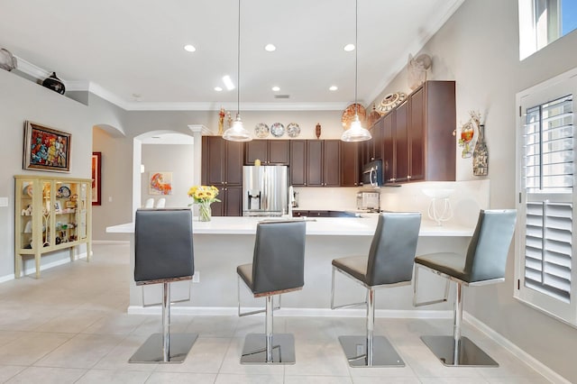 kitchen featuring dark brown cabinetry, appliances with stainless steel finishes, a kitchen breakfast bar, decorative light fixtures, and light countertops