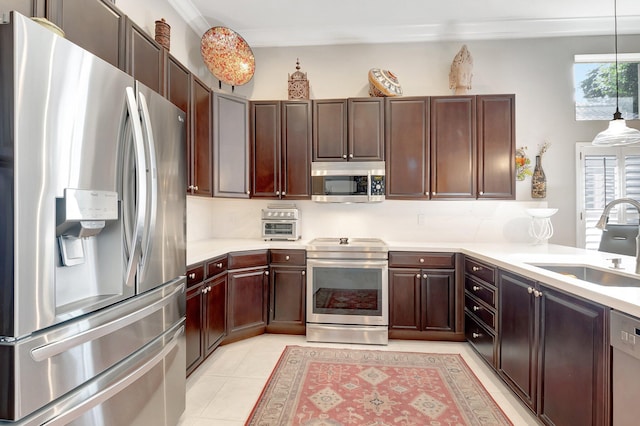 kitchen with stainless steel appliances, light countertops, a sink, and decorative light fixtures