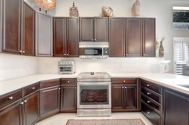 kitchen with light tile patterned floors, light countertops, backsplash, appliances with stainless steel finishes, and dark brown cabinetry