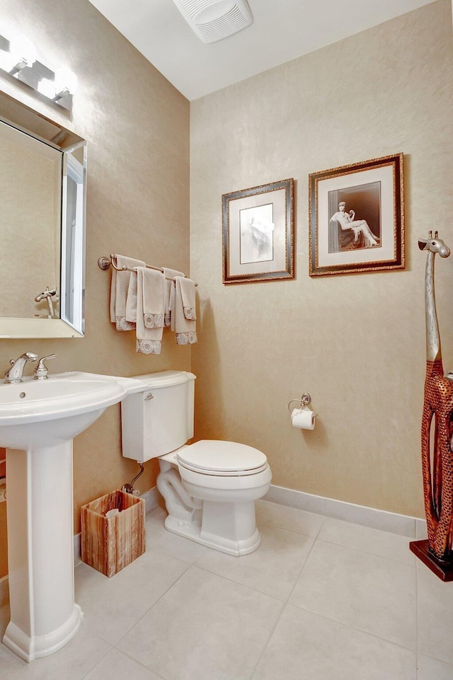 half bath featuring baseboards, visible vents, toilet, and tile patterned floors