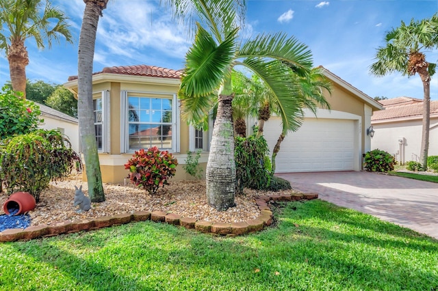 mediterranean / spanish-style house with an attached garage, a tiled roof, decorative driveway, stucco siding, and a front lawn