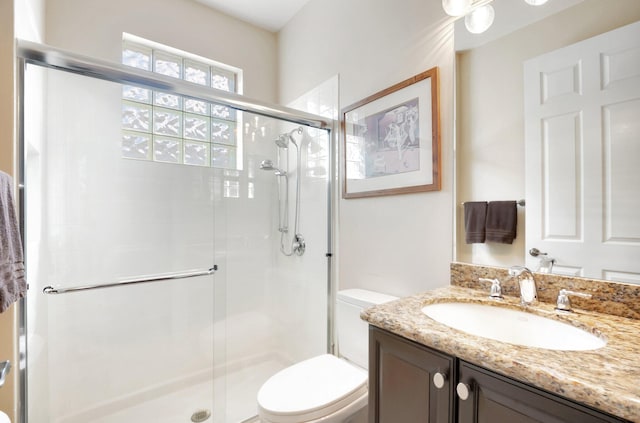 bathroom featuring toilet, a stall shower, and vanity