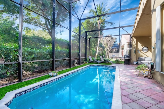 pool featuring glass enclosure, a patio area, and grilling area