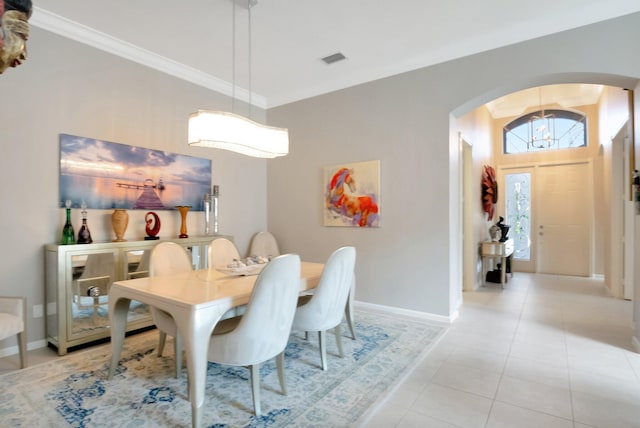 dining room with arched walkways, crown molding, light tile patterned floors, visible vents, and baseboards