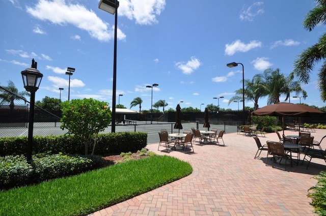 view of home's community featuring a tennis court and fence