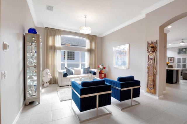 living area featuring baseboards, visible vents, arched walkways, and crown molding