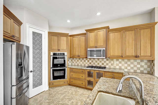 kitchen with sink, light stone countertops, tasteful backsplash, and stainless steel appliances