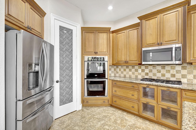 kitchen with appliances with stainless steel finishes, light stone countertops, and decorative backsplash