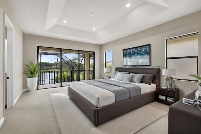 bedroom featuring access to outside, a water view, light colored carpet, and a tray ceiling