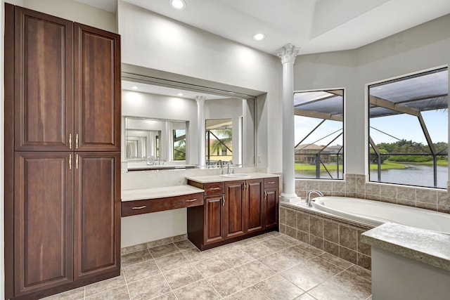 bathroom featuring a water view, vanity, tiled tub, and ornate columns