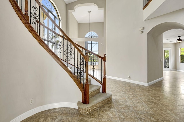 stairs featuring ceiling fan and a towering ceiling