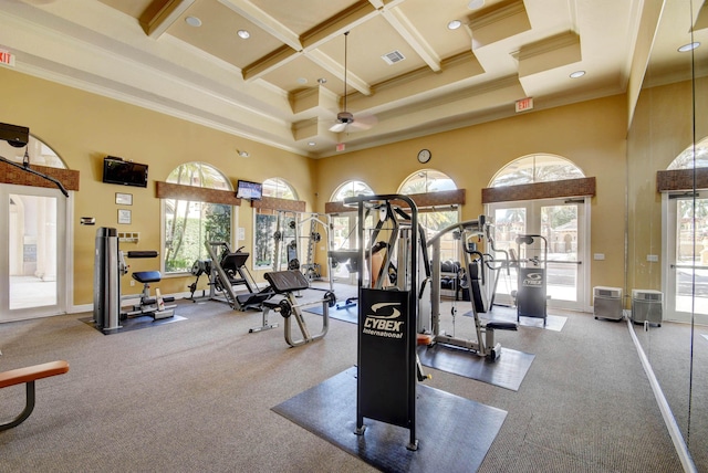 exercise room featuring ceiling fan, coffered ceiling, crown molding, and a towering ceiling