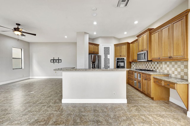 kitchen with a kitchen island, stainless steel appliances, light stone countertops, and backsplash