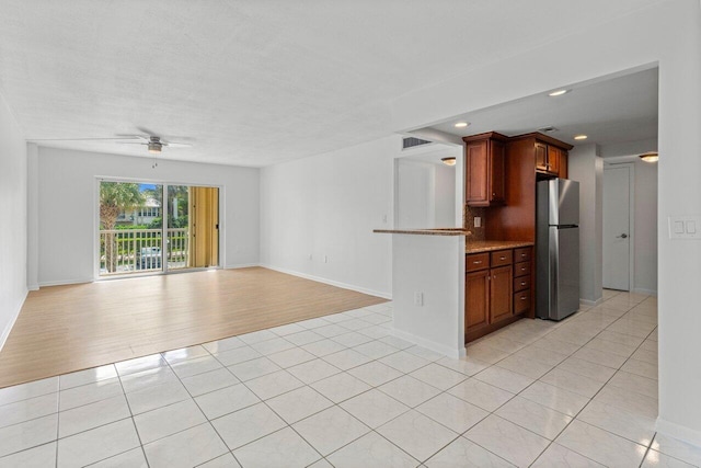 kitchen with open floor plan, light countertops, light tile patterned floors, and freestanding refrigerator