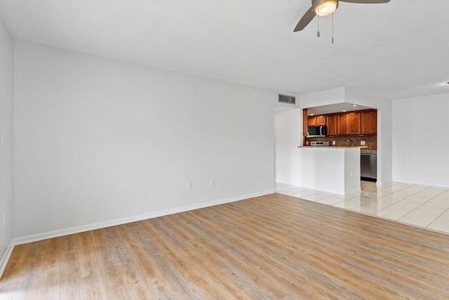 unfurnished living room featuring baseboards, visible vents, ceiling fan, and light wood finished floors