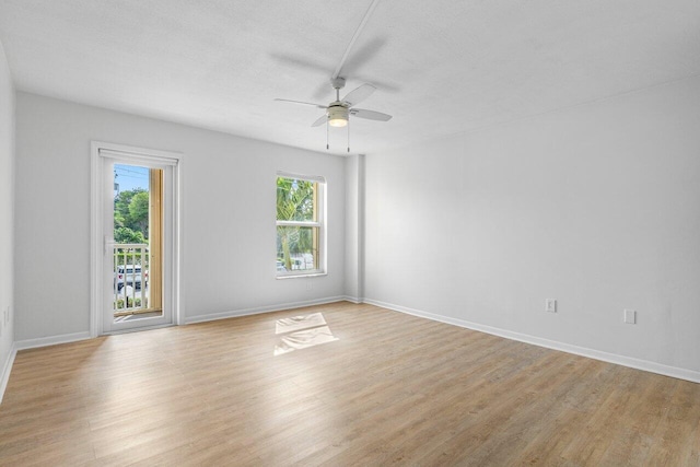 empty room with light wood-style flooring, baseboards, ceiling fan, and a textured ceiling