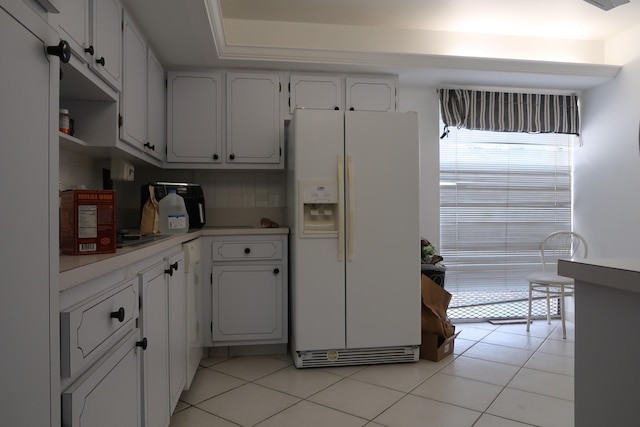 kitchen with light tile patterned floors, white refrigerator with ice dispenser, decorative backsplash, light countertops, and white cabinetry