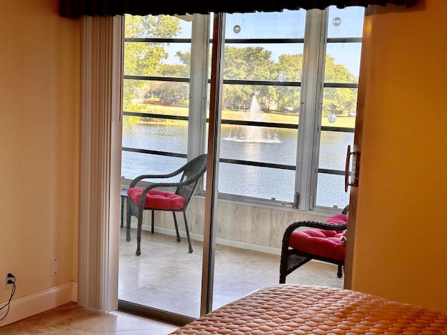 doorway to outside featuring a water view, baseboards, and light tile patterned floors