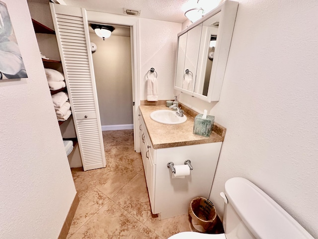 half bathroom with a closet, visible vents, toilet, vanity, and baseboards