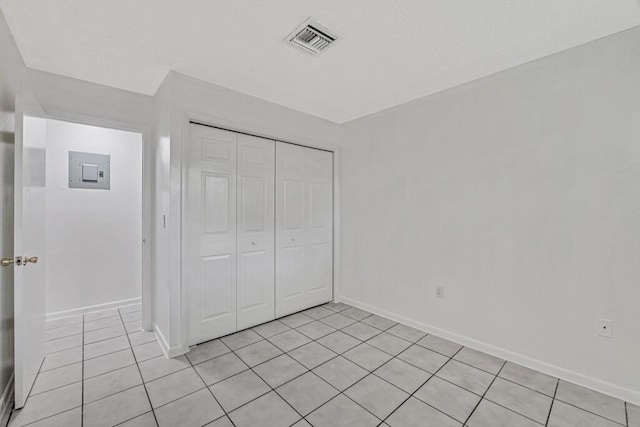 unfurnished bedroom featuring electric panel, light tile patterned flooring, and a closet