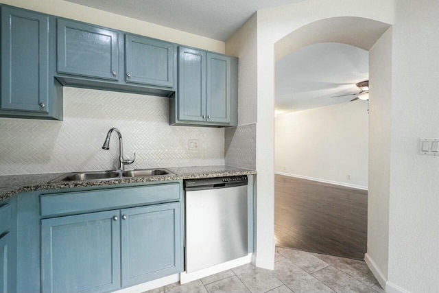 kitchen with blue cabinets, sink, stainless steel dishwasher, and decorative backsplash