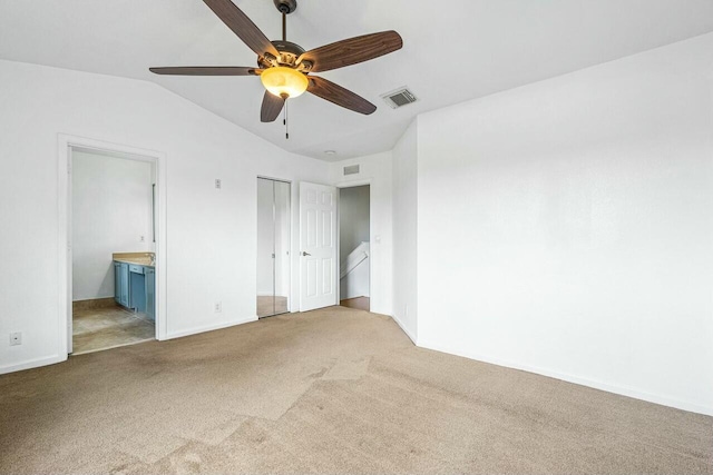 unfurnished bedroom featuring ensuite bathroom, lofted ceiling, ceiling fan, and carpet floors