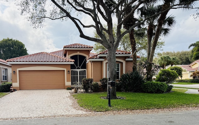 mediterranean / spanish home featuring a front yard, decorative driveway, an attached garage, and stucco siding