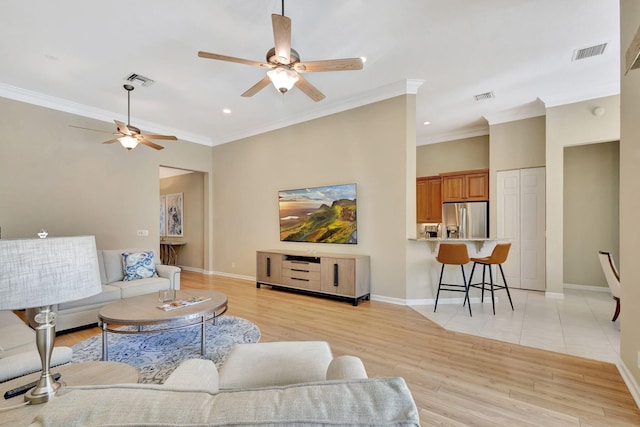 living area with ornamental molding, visible vents, and light wood-type flooring