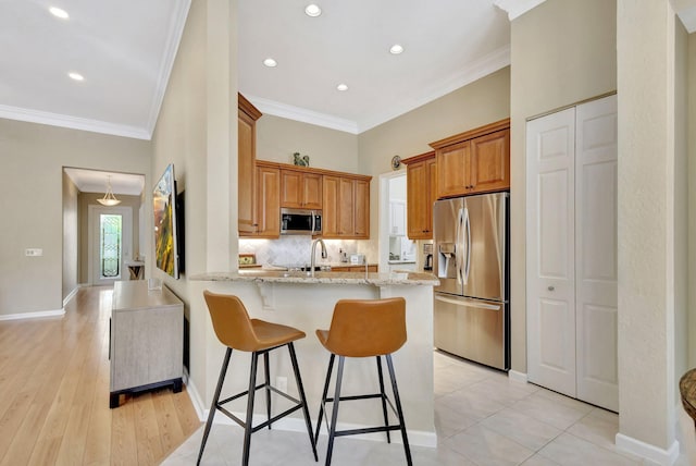 kitchen with light stone counters, brown cabinets, stainless steel appliances, and a peninsula