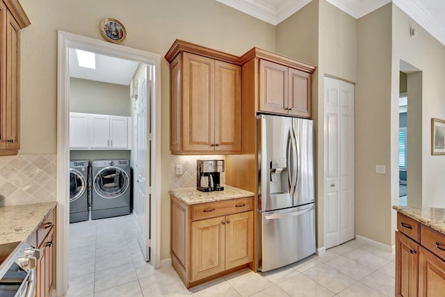 kitchen with light tile patterned flooring, washer and dryer, light stone countertops, stainless steel fridge with ice dispenser, and stove