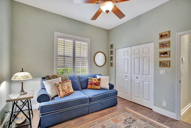 living area featuring baseboards, ceiling fan, and wood finished floors