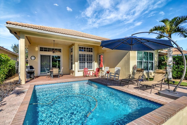 outdoor pool with a ceiling fan, a grill, and a patio area