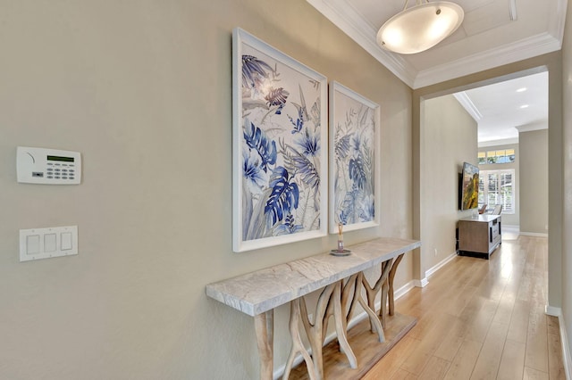 hallway featuring crown molding, baseboards, and light wood-type flooring