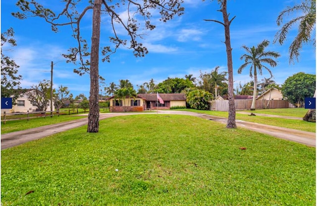 view of front of property with a front lawn, curved driveway, and fence