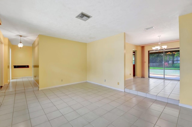 empty room with baseboards, visible vents, an inviting chandelier, and light tile patterned flooring