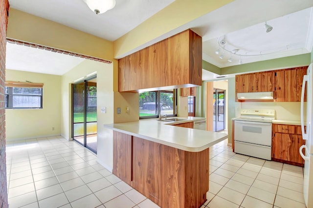 kitchen featuring white range with electric cooktop, light countertops, brown cabinetry, a peninsula, and under cabinet range hood