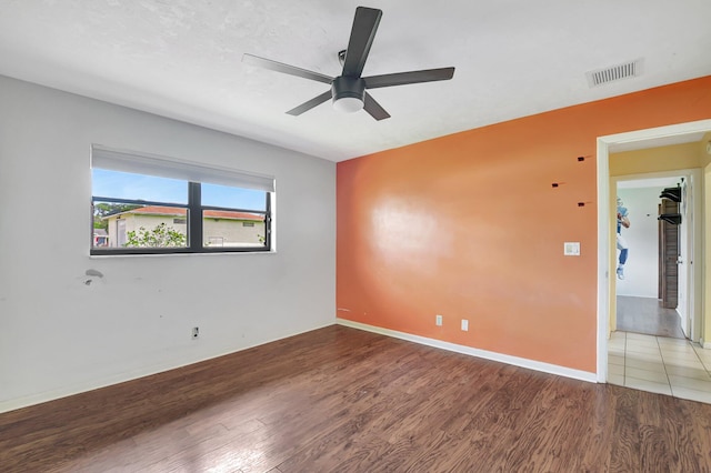 empty room with a ceiling fan, visible vents, baseboards, and wood finished floors