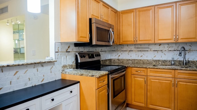 kitchen featuring stainless steel appliances, brown cabinets, a sink, and light stone counters