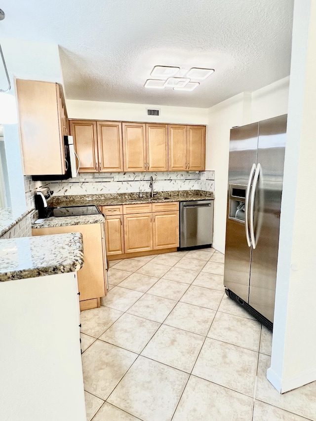 kitchen with light tile patterned floors, stainless steel appliances, a sink, visible vents, and tasteful backsplash