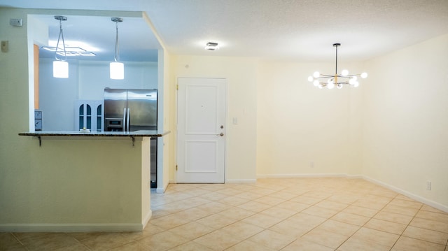 kitchen featuring dark stone counters, hanging light fixtures, stainless steel refrigerator with ice dispenser, and a textured ceiling