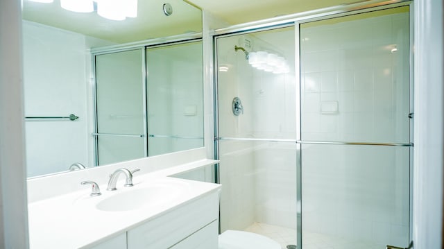 bathroom with toilet, a shower stall, and vanity