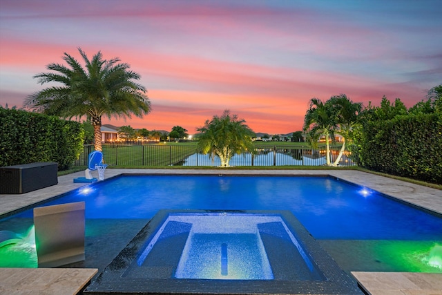 pool at dusk featuring a water view and an in ground hot tub