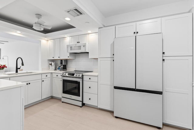 kitchen with refrigerator, stainless steel electric range oven, light countertops, visible vents, and white cabinetry