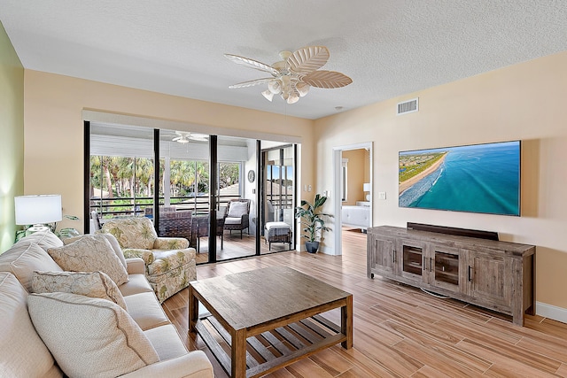 living room featuring a textured ceiling, light wood-style floors, visible vents, and ceiling fan