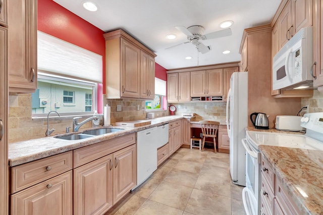 kitchen featuring tasteful backsplash, white appliances, light stone countertops, and a sink